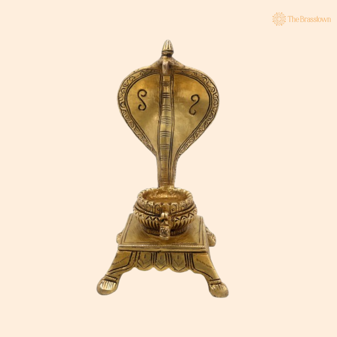 A brass naga shivling idol with a cobra hood design on a decorative base, representing a serpent deity.